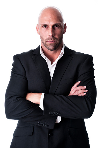 angry bald businessman (bodyguard, bouncer) with arms crossed isolated on white staring at camera