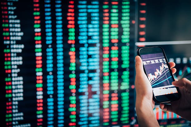 istock cell phone on hand with stock market data background 536455989