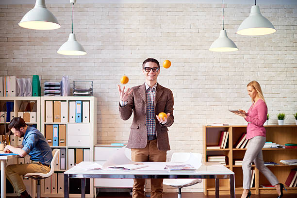 Keep calm and juggle on Joyful designer juggling with oranges at design studio juggling stock pictures, royalty-free photos & images