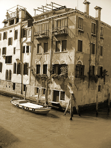 Venice, Italy- October 10, 2011: A small canal that leads to the Grand Canal in Venice.  This commercial and residential area has several boats which are moored along the fondamente, or walkway. A small arched bridge is in the background.