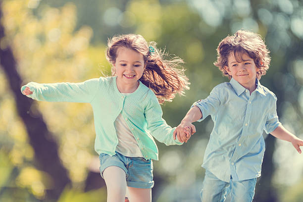 Two smiling kids holding hands and having fun in nature.