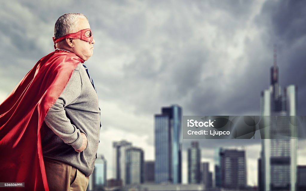 Senior superhero standing in front of a city Senior superhero standing in front of a dark city Senior Adult Stock Photo