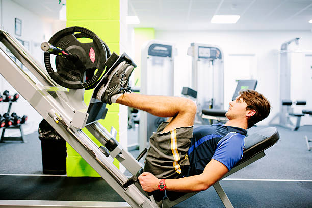 musculação na sala de ginástica, usando uma pressão de pernas - weight training body building men human muscle - fotografias e filmes do acervo