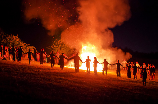 People holding hands around a fire
