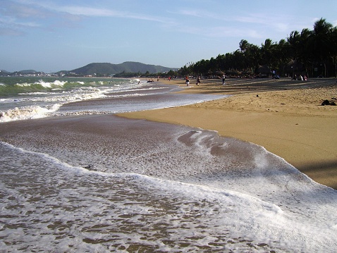 Beautiful long stretch of sandy beach in Nha Trang. Tourists and locals relax and sunbathing.