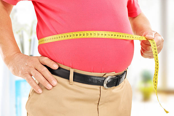 Close-up on a man measuring his belly Close-up on a man measuring his belly at home body conscious stock pictures, royalty-free photos & images