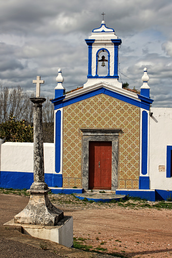 Whitewashed catholic church with blue trimming in Vila Vicosa, Altantejo, Portugal under cloudy sky