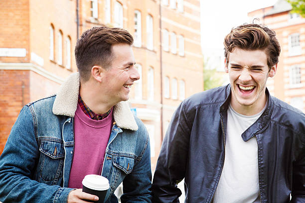 junge männer mit einem gut lachen während der fahrt zu fuß - english culture talking men listening stock-fotos und bilder