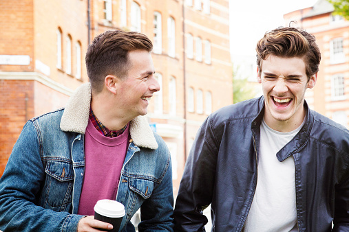 Young men having a good laugh while commuting on foot. Shot in London, UK.