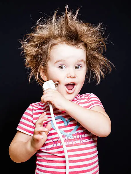 Little girl screaming with a plug in hand and with punk hair.