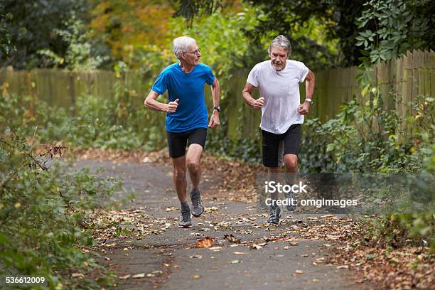 Two Mature Male Joggers Running Along Path Stock Photo - Download Image Now - Jogging, Mature Adult, People