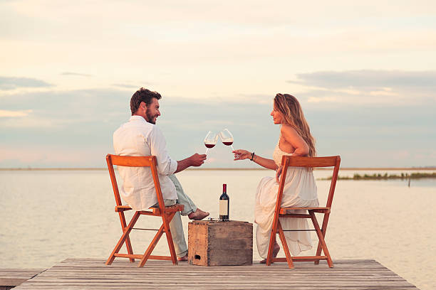 couple drinking red wine at the seaside on a jetty stock photo