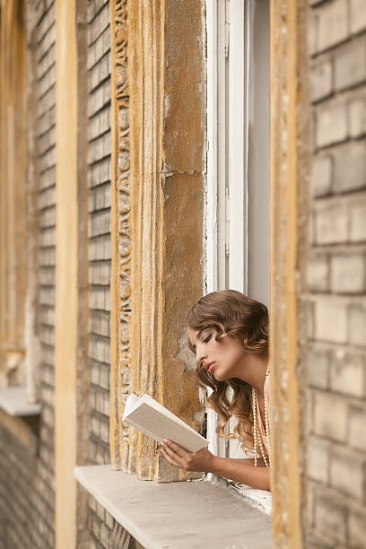 istock retro girl reading a book in the window 536616179