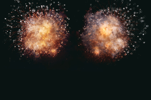 Golden fireworks explode like nebula. Blooming in the night sky.