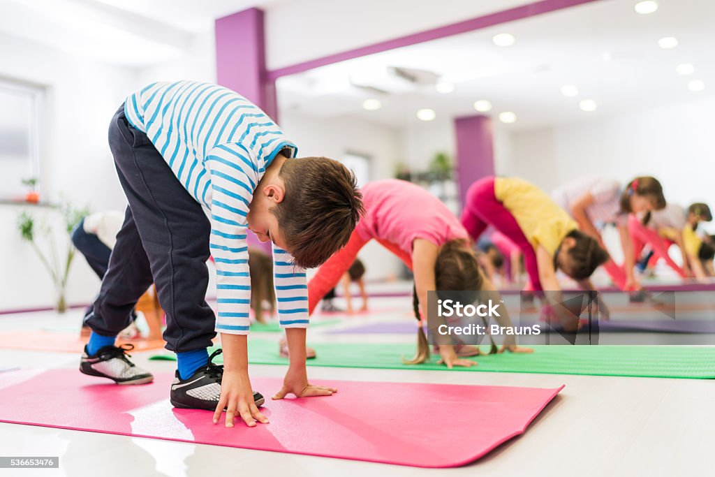 Grupo de los niños de estiramiento sus piernas en una formación deportiva. - Foto de stock de Niño libre de derechos