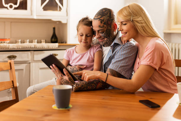 sorridente genitori navigare in internet con la figlia sul touchpad. - child digital tablet mother teaching foto e immagini stock