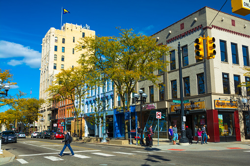 Ann Arbor, United States - October 18, 2015: Pedestrians walking on and crossing Main street in Downtown Ann Arbor, with the historic First National Bank building at the end of the block.