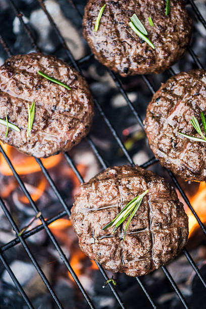 burning beef burgers on bbq flames stock photo
