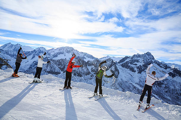 Skiing. Warm Up. Stretching before a skiing class on the mountain slope. Group of skiiers enjoying sunny day on the top of a mountain.
