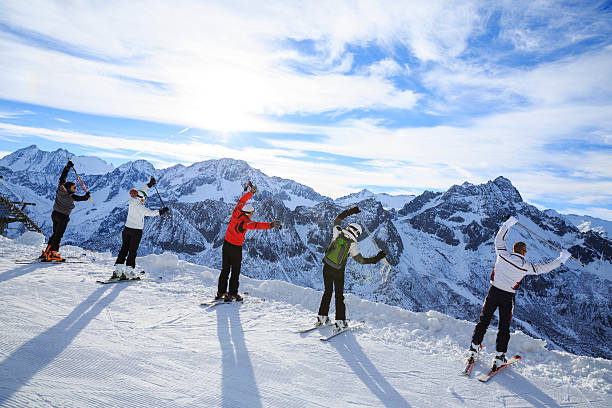 Skiing   Warm Up   Happy skier class on the mountain top Skiing. Warm Up. Stretching before a skiing class on the mountain slope. Group of skiiers enjoying sunny day on the top of a mountain. ski instructor stock pictures, royalty-free photos & images