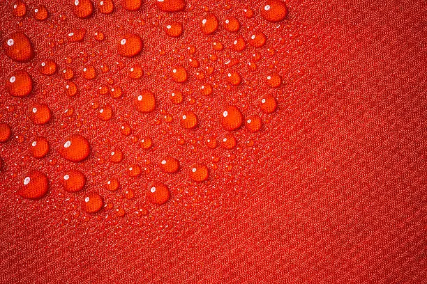 Red waterproof fabric close up with water beads