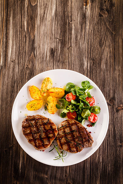 istock Beef steaks, baked potatoes and vegetable salad 536665692