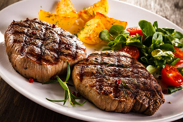 istock Beef steaks, baked potatoes and vegetable salad 536665928