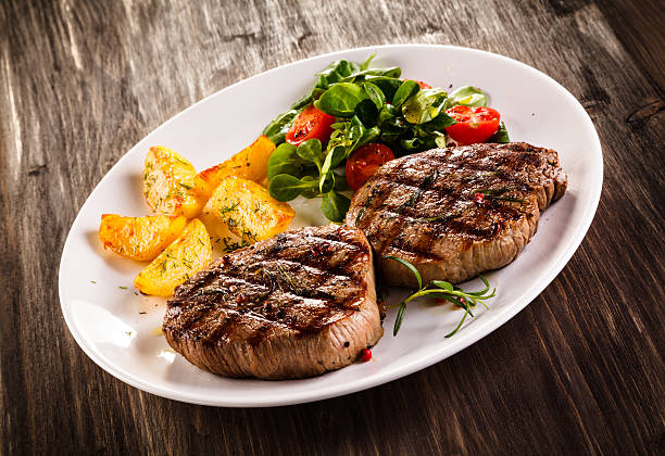 istock Beef steaks, baked potatoes and vegetable salad 536666024