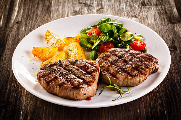 bistecs de carne de res, papas al horno y una ensalada de vegetales - steak grilled beef plate fotografías e imágenes de stock