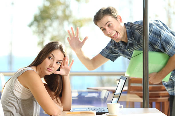 Girl ignoring a stalker man waving Girl ignoring and rejecting to a stalker man waving her in a coffee shop in a blind date old style stock pictures, royalty-free photos & images