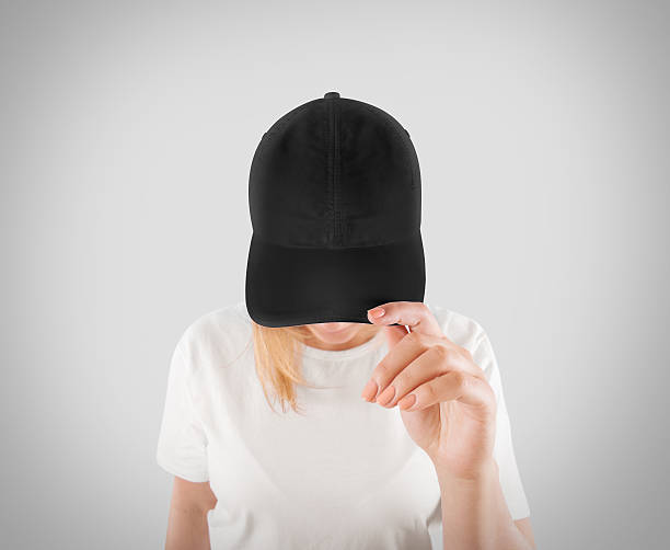 Blank black baseball cap mockup template, wear on women head Blank black baseball cap mockup template, wear on women head, isolated, clipping path. Woman in gray hat and t shirt uniform mock up holding visor of caps. Cotton basebal cap design on delivery guy. cotton mill stock pictures, royalty-free photos & images