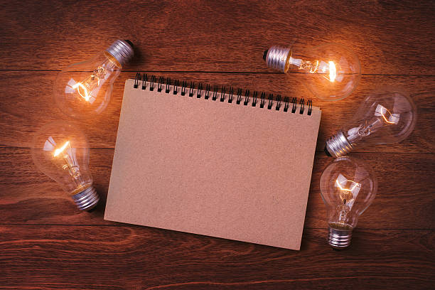 istock Light bulb and book on wooden table. 536670746