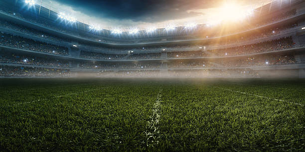 Dramatic american football stadium A wide angle panoramic image of a outdoor american football stadium full of spectators under evening sky. The image has depth of field with the focus on the foreground part of the pitch. The view from center of the field. soccer field stock pictures, royalty-free photos & images