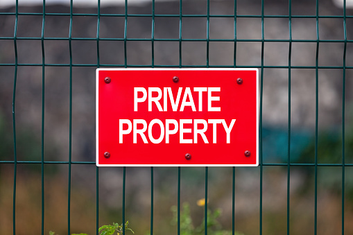 Red placard attached to a fence stating “