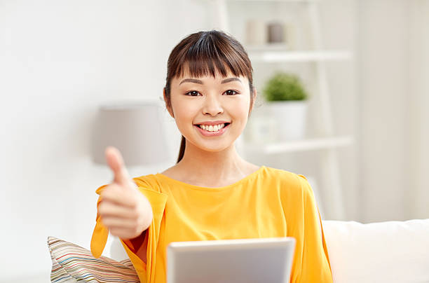 istock happy asian woman with tablet pc and thumbs up 536675994