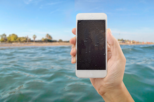 man using his phone wet in a beach in summer