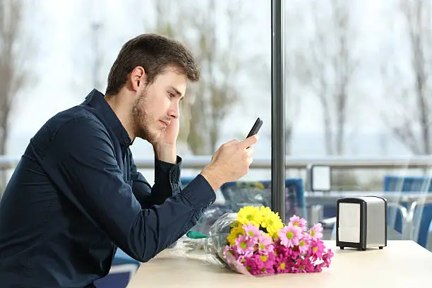 Photo of Man stood up in a date checking phone messages