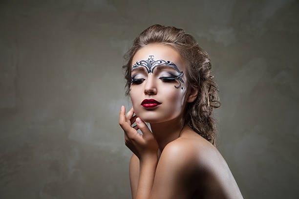 istock Sensual woman with face art and red lips looking down 536680674