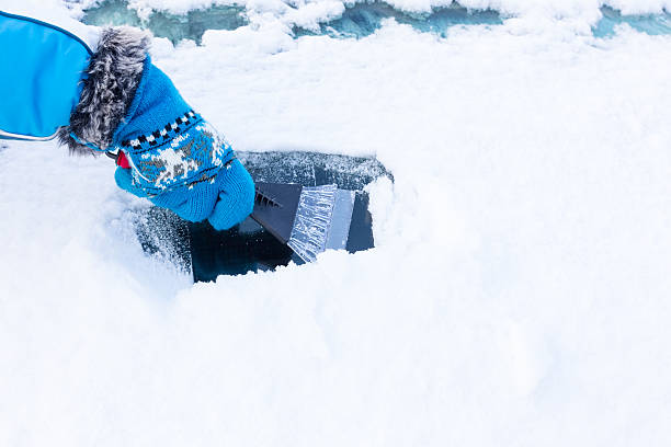 istock Hand in glove holding ice scraper scratching snow from windshield 536681879