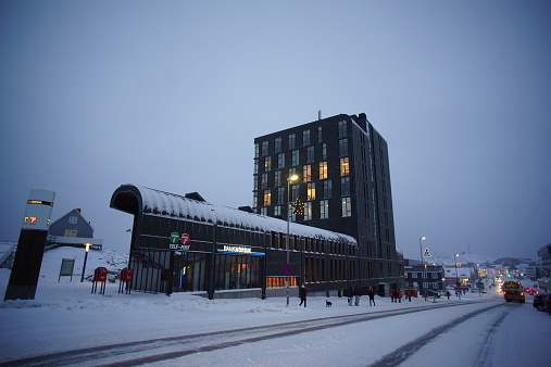 Nuuk, Greenland - November 24, 2014: Building of post office and bank in Nuuk. People walk on the road in a snowing day.