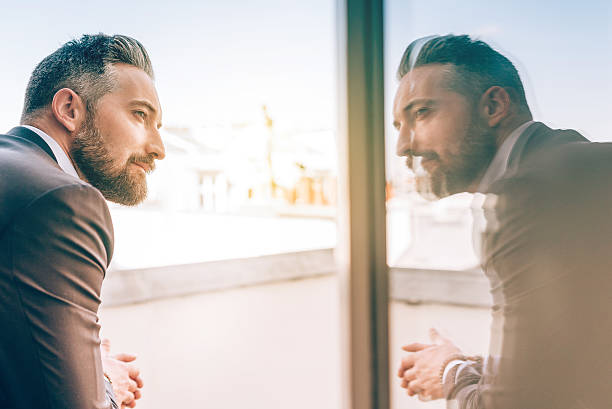 bearded business man reflecting himself in window glass bearded business man reflecting himself in window glass looking in mirror stock pictures, royalty-free photos & images