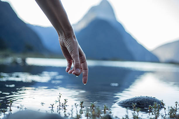 istock Finger touches surface of mountain lake 536684808