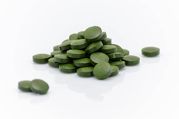 verde chlorella spirulina algas pílulas sobre branco grande plano - chlorella spirulina bacterium algae nutritional supplement imagens e fotografias de stock