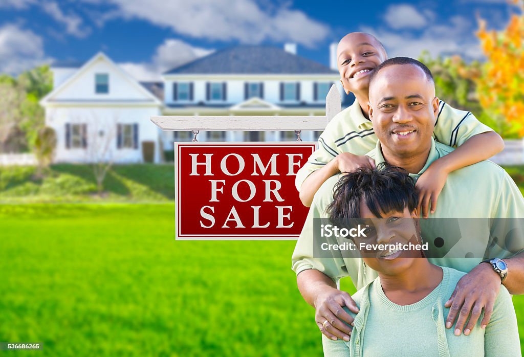 African American Family In Front of Sale Sign and House Happy African American Family In Front of For Sale Real Estate Sign and House. 2015 Stock Photo