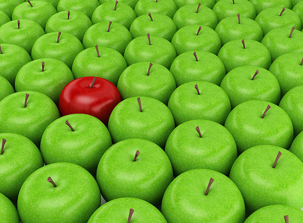 Red apple on a background of green apples Red apple selected on the background of green apples self coloured stock pictures, royalty-free photos & images