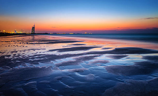 strand im sonnenuntergang  - dubai beach hotel skyline stock-fotos und bilder