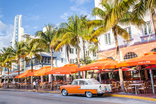  Miami Beach, Florida, USA - April 25, 2016:   View along Ocean Drive along South Beach Miami in the historic Art Deco District with hotels, restaurant, people and classic car visible.  South Beach has been  a notable tourist destinations for many years. 