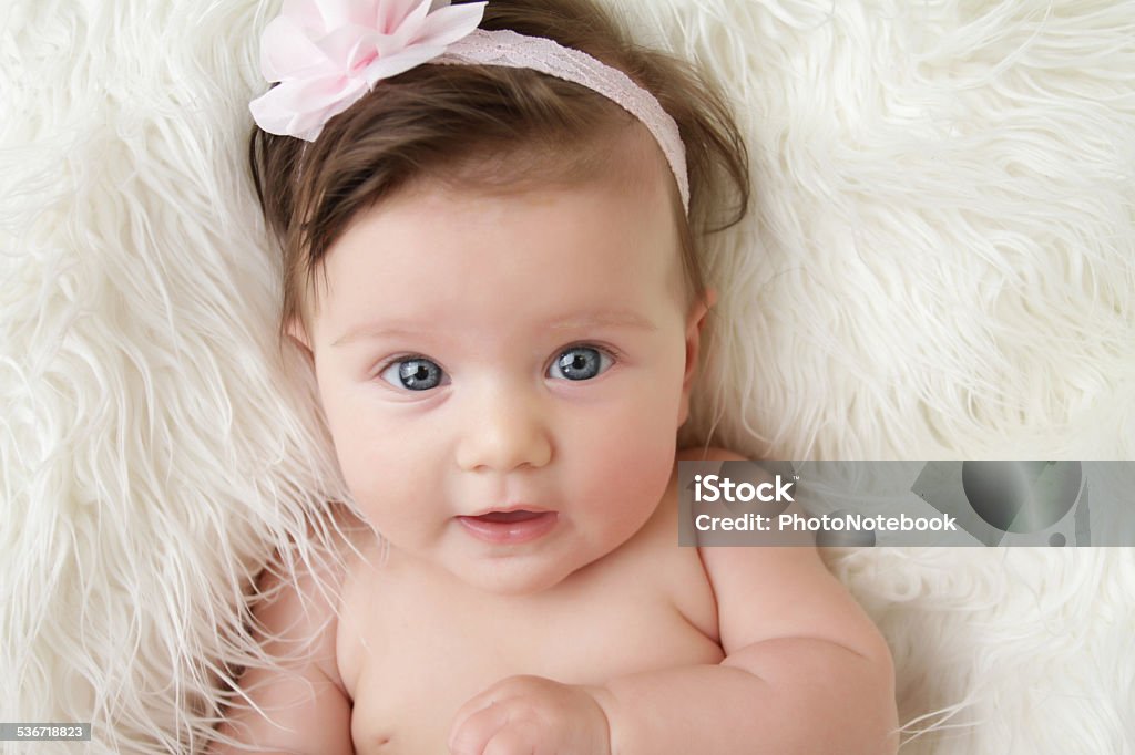 Newborn Baby Newborn baby girl posed in a bowl on her back, on blanket of fur, smiling looking at camera 2015 Stock Photo