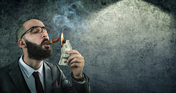 burn wealth concept: adult burning a $ 100 bill