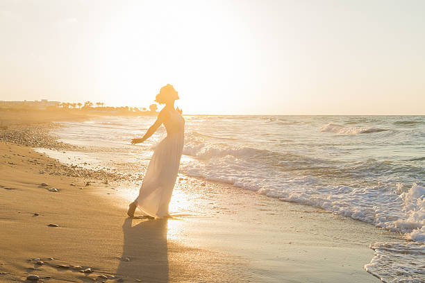 istock Young woman enjoys walking on a hazy beach at dusk. 536722067
